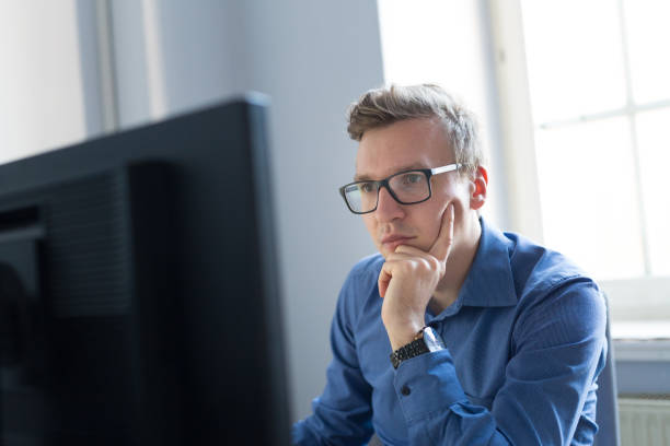 istock Casual businessman working in office, sitting at desk, typing on keyboard, looking at computer screen. 922719604