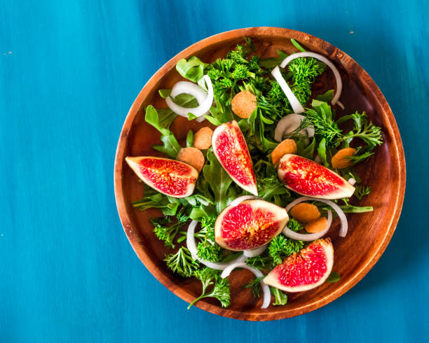 istock Autumn salad of arugula, figs in a brown earthenware plate on a blue background. top view 922720256