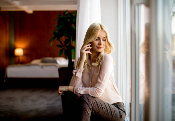 istock Pretty young woman with mobile phone by the window 922726852