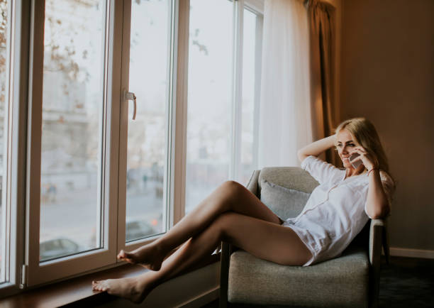 istock Pretty young woman with mobile phone by the window 922726904