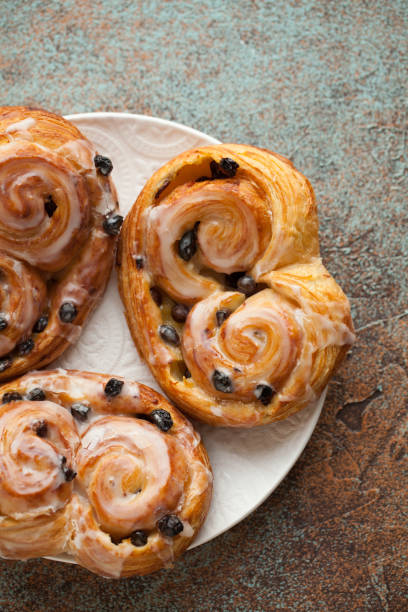 istock Fresh buns with raisins and icing on old rusty background. Top view 922727862