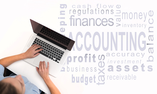 Woman using her laptop over accounting word-cloud
