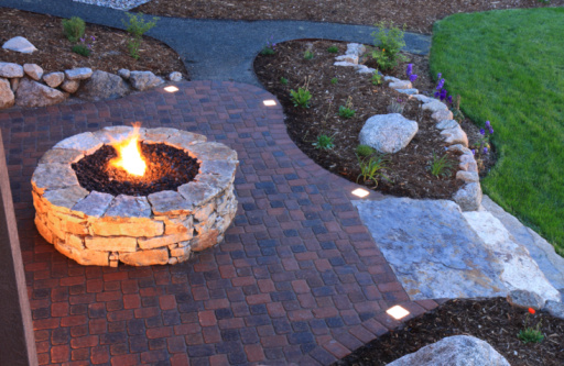 Aerial shot of fire pit and landscape pavers at dusk. Paver patio has built in lighted pavers.