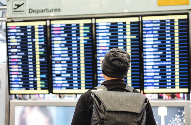 istock a man with backpack looking on departure flight information board, for travel, go back home and holiday trip 922734110