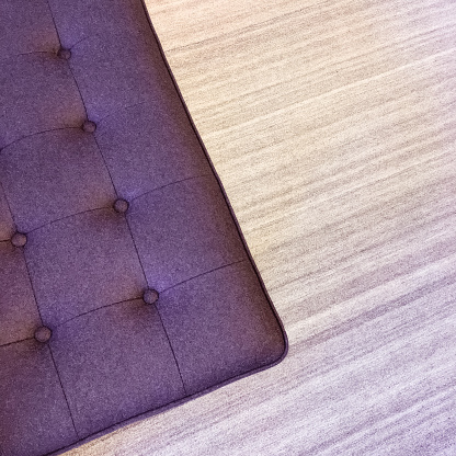 Close-up of a purple ottoman on a striped carpet. Modern furniture.