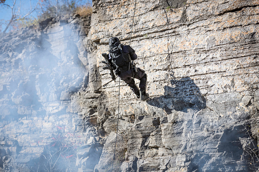 Swat Police Officer Rappelling in full dressed uniform with firearms