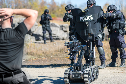 Police Swat Team Officers Using a Mechanical Robot Unit and placing a man under arrest