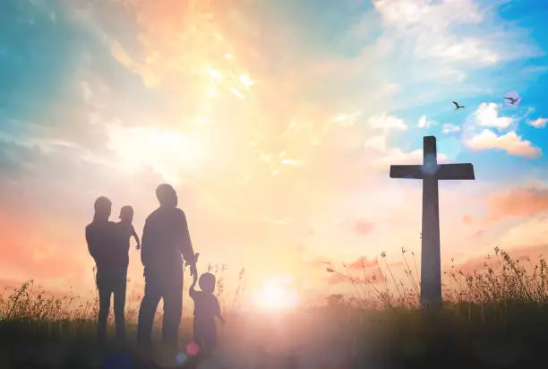 Silhouette father mother and two son looking for the cross on autumn sunrise background