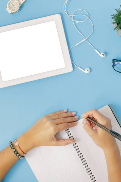 istock Education background. Female hands write in a notebook on a blue background, top view 922742346