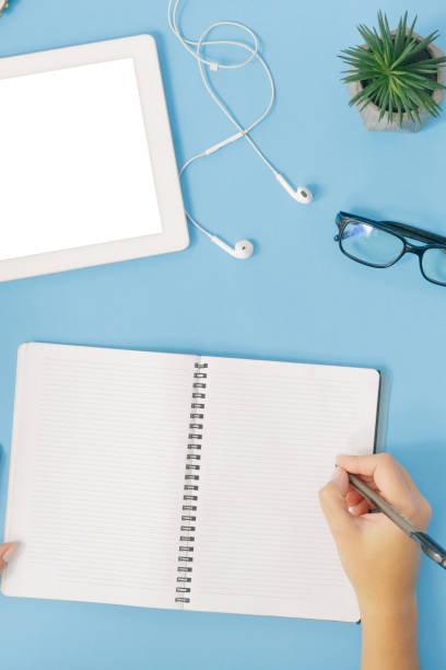 istock Female office workplace concept. Female hand writes in notebook, top view 922742392