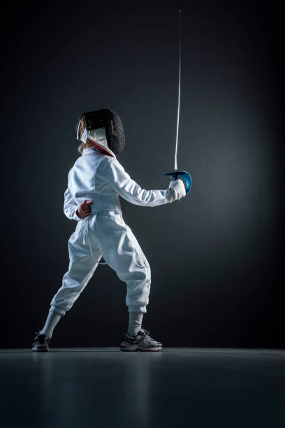 istock Boy practicing fencing sport over black background 922744870