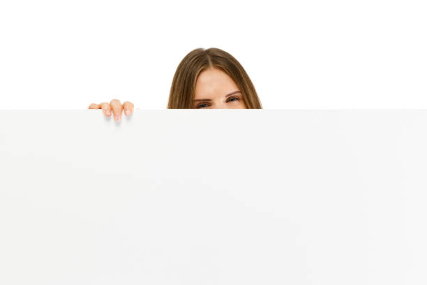 istock Young attractive girl peeking behind blank board on white background 922746614