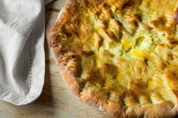 Scrumptious Appetizing Whole Round Flatbread with Cheese Filling on Wooden Table with White Napkin. Traditional Savory Pastry of Middle Eastern Oriental Mediterranean Indian Levantine Cuisines. Top View
