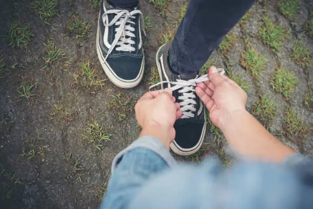 Photo of Hipster boyfriend tying shoes to his girls while go the relaxing in holiday, Couple in love concept.