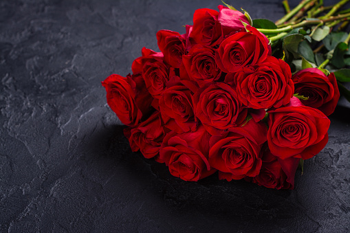 Bunch of red roses on black stone background. Copy space