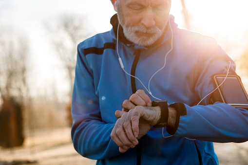 Elderly Man using Smart Watch measuring heart rate during walk