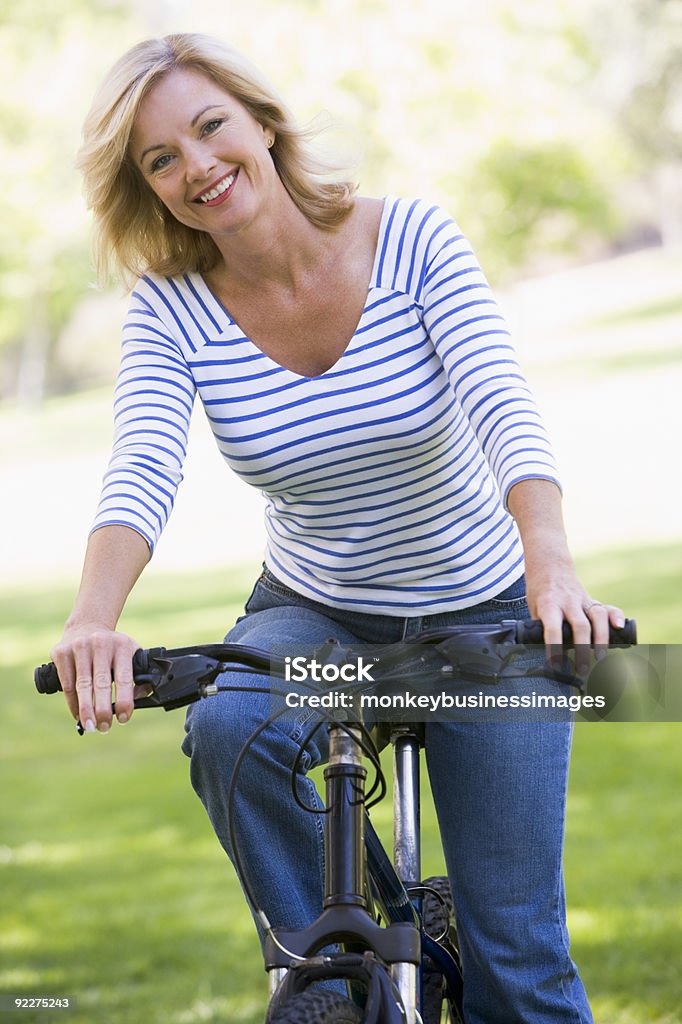 Mujer en bicicleta al aire libre - Foto de stock de Mujeres maduras libre de derechos