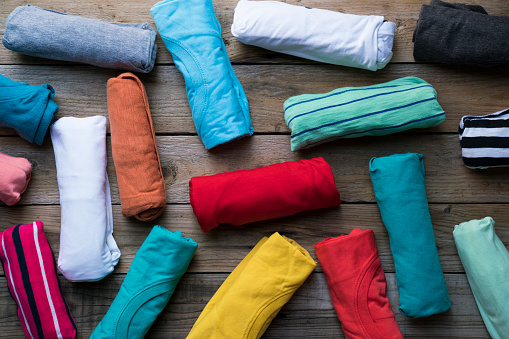close up of rolled colorful clothes on wooden table background