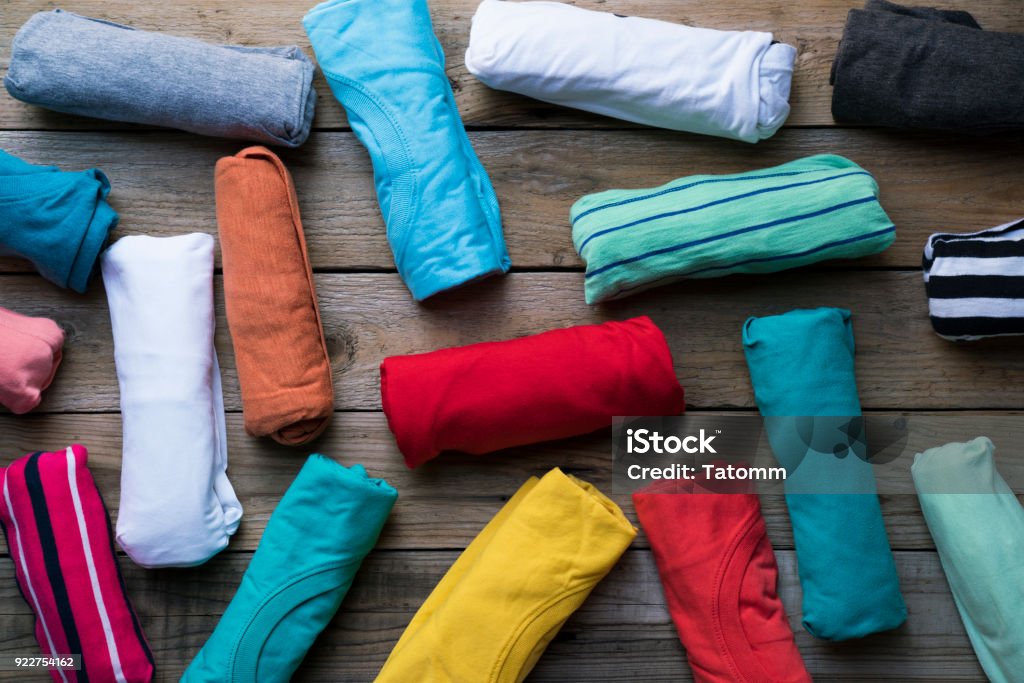 close up of rolled colorful clothes on wooden table background Rolled Up Stock Photo