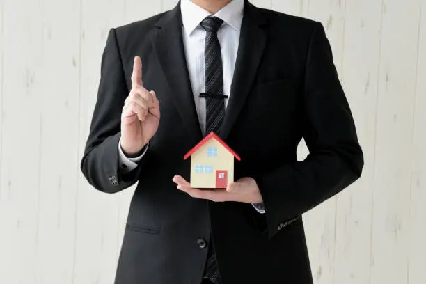 Photo of Business man having toy of house with pointing sign