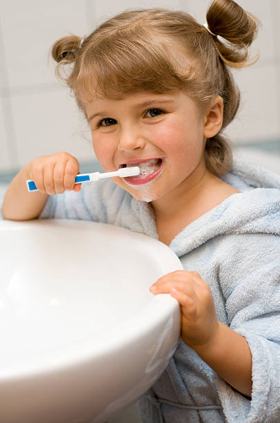 Little girl brushing teeth in bathroom stock photo