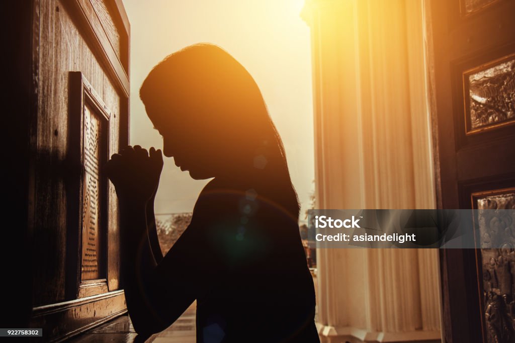 silhouette de femme à genoux et de prier dans l’église moderne au moment du coucher du soleil - Photo de Confession libre de droits