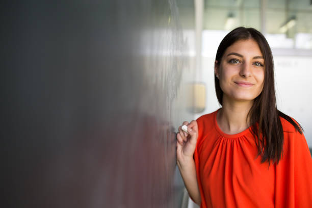 Pretty, young college student writing on the chalkboard/blackboard Pretty, young college student writing on the chalkboard/blackboard during a math class math woman stock pictures, royalty-free photos & images