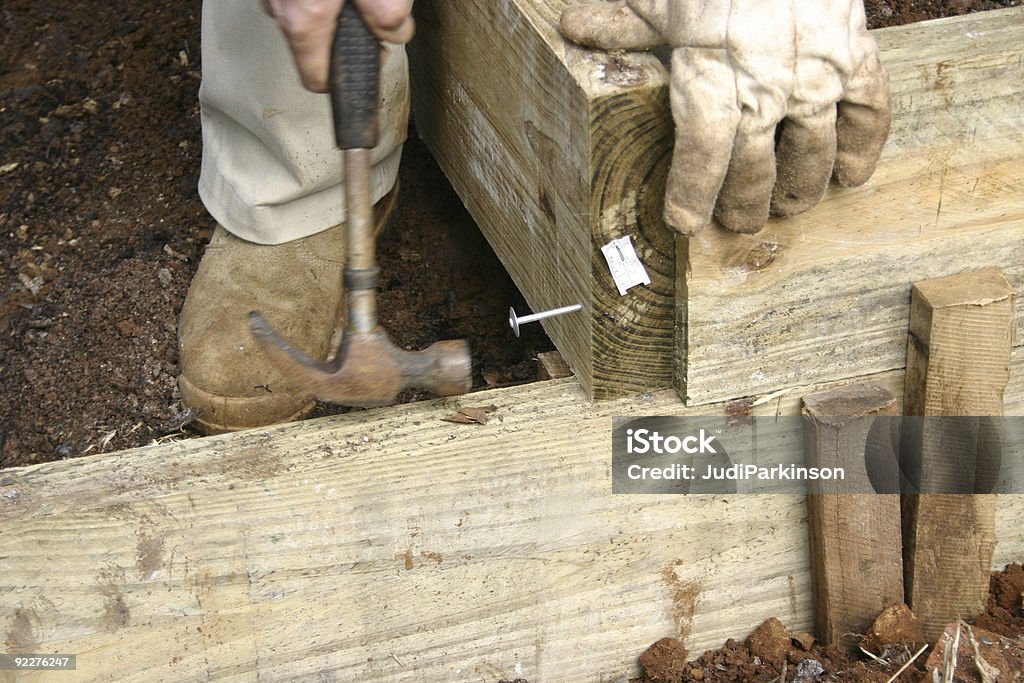 Hammering amplio clavo en la pared de madera al jardín - Foto de stock de Parterre libre de derechos
