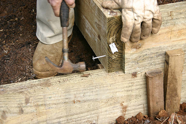 Hammering Large Nail into Wooden Garden Wall