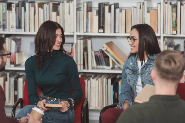 istock smiling girls sitting in library and looking at each other 922764720