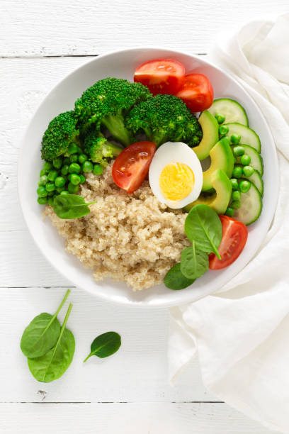 istock Healthy detox dish with egg, avocado, quinoa, spinach, fresh tomato, green peas and broccoli on white wooden background, top view 922767704