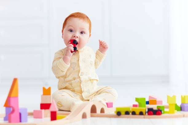 cute ginger baby playing with toy railway road at home. Tasting wagon