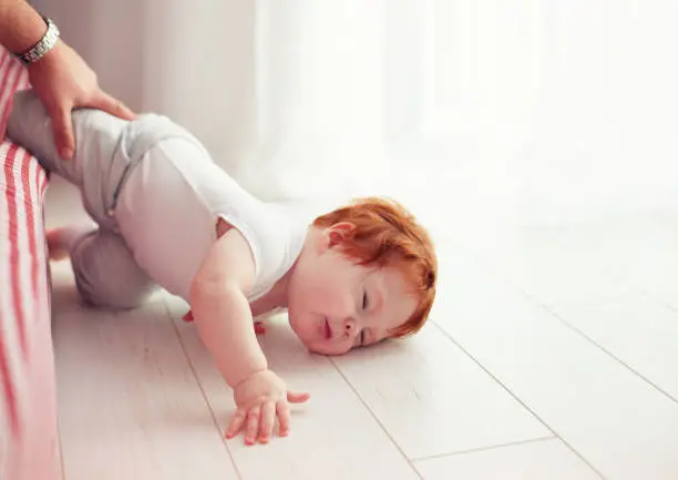 Poor little toddler baby fell down from the bed while crawling on it. Dad missed to catch him