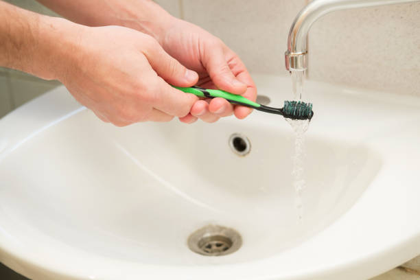 istock male hand with a toothbrush should be washed in clean water 922773822