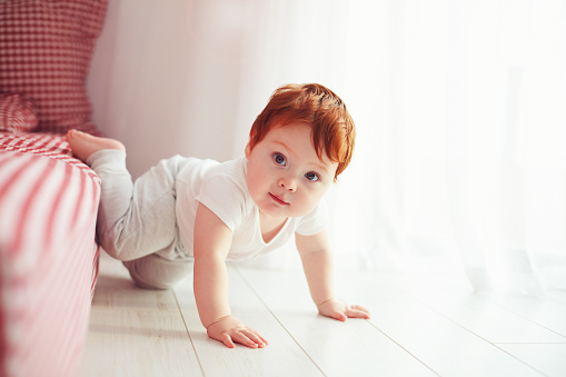 cute toddler baby getting off the bed, crawling at home