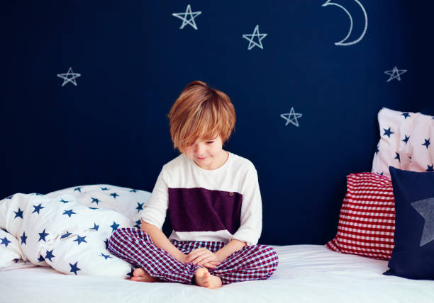istock cute smiling kid in pajamas sitting in bed 922774270