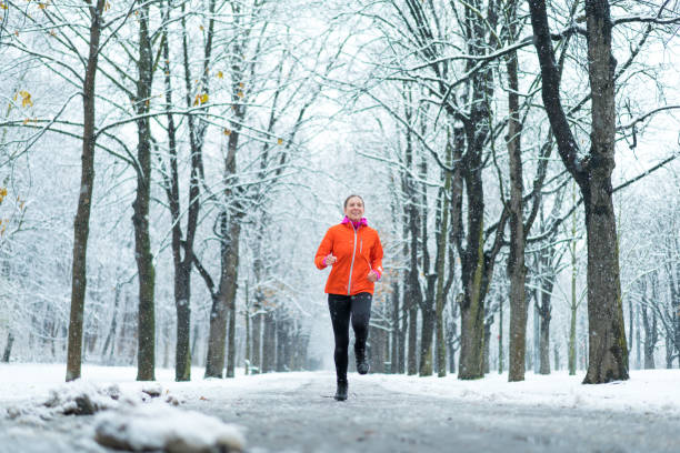 istock happy 43 year old woman jogging on road through winter forest 922774892