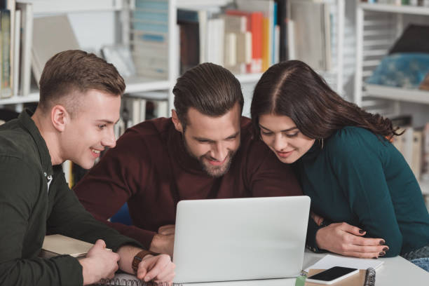 istock smiling friends looking at laptop in library 922775260