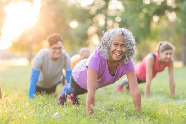 fitness-klasse im freien - yoga exercising outdoors group of people stock-fotos und bilder