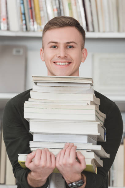 istock smiling student holding stack of books and looking at camera 922775854