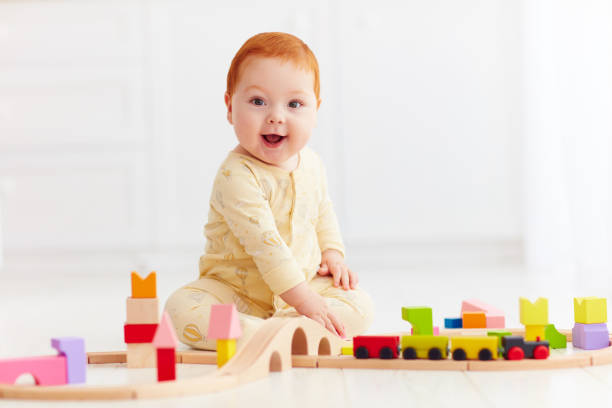 istock cute ginger baby playing with toy railway road at home 922776436