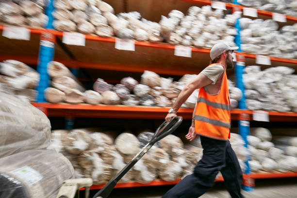 istock Male worker pulling rugs on pallet jack in factory 922777732
