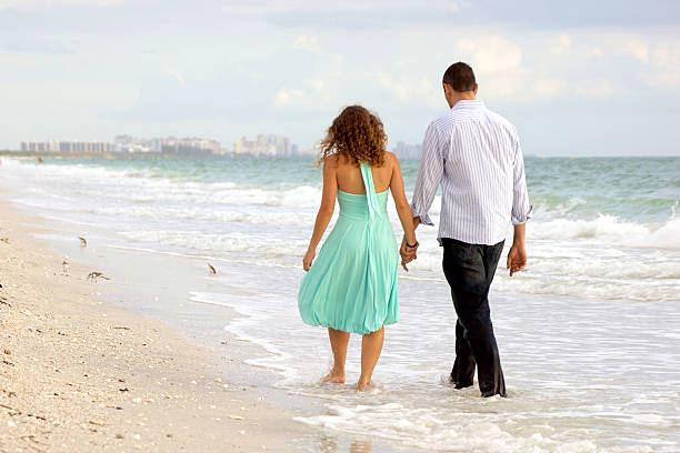 jeune couple marchant main dans la main sur la plage thier - bonita springs photos et images de collection
