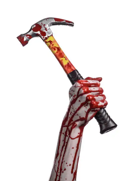 Photo of Bloody halloween theme: bloody hand holding a bloody hammer isolated on a white background