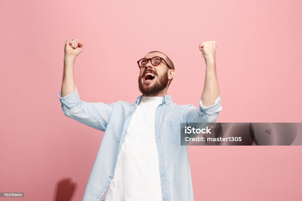 Winning success man happy ecstatic celebrating being a winner. Dynamic energetic image of male model I won. Winning success happy man celebrating being a winner. Dynamic image of caucasian male model on pink studio background. Victory, delight concept. Human facial emotions concept. Trendy colors Men Stock Photo