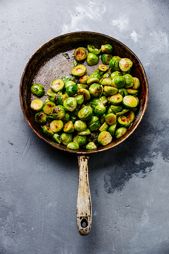 fried Brussels sprouts in frying pan on concrete background