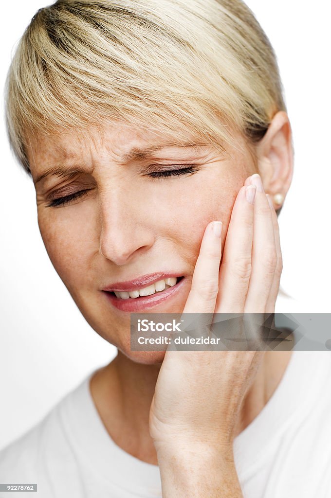 Woman grabbing her cheek symbolizing tooth pain blond young woman in pain close up shoot Adult Stock Photo