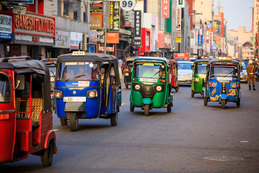 Colombo, Sri Lanka - December 7, 2016: Traffic and busy street in the center of Colombo, the capital city of Sri Lanka. Tuktuk taxi, the motorized development of the traditional pulled rickshaw, ride on a city street.
