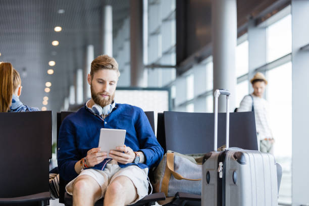 istock Young bearded man using digital tablet in airport lounge 922797628
