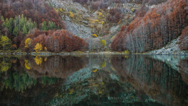 Mountain, trees and fall foliage in perfect lake reflections (Lago Santo, Modena, Italy)